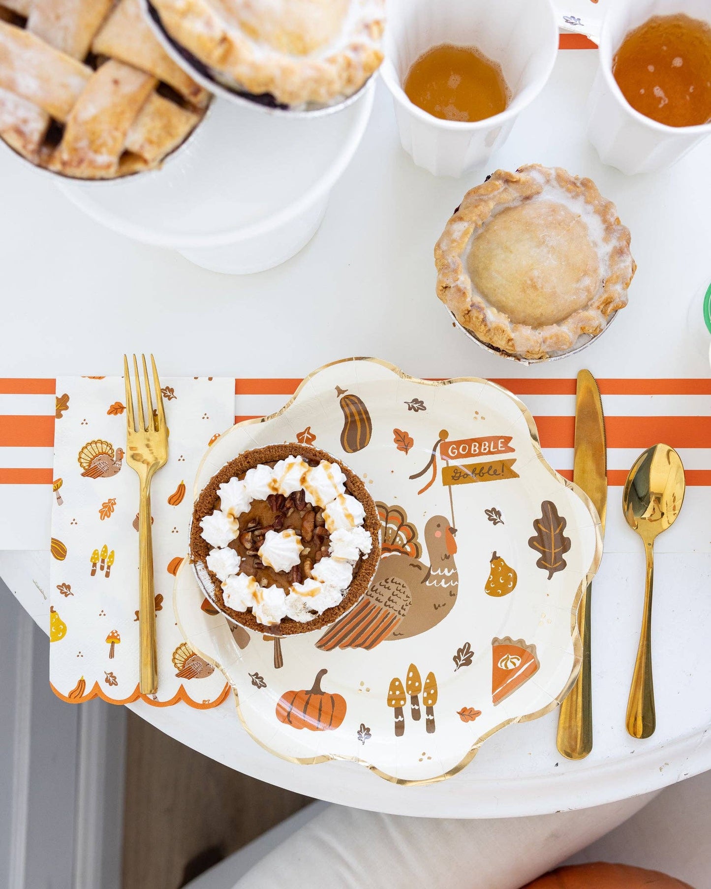 Thanksgiving-themed table setting with a plate, napkin, cutlery and pumpkin pie.