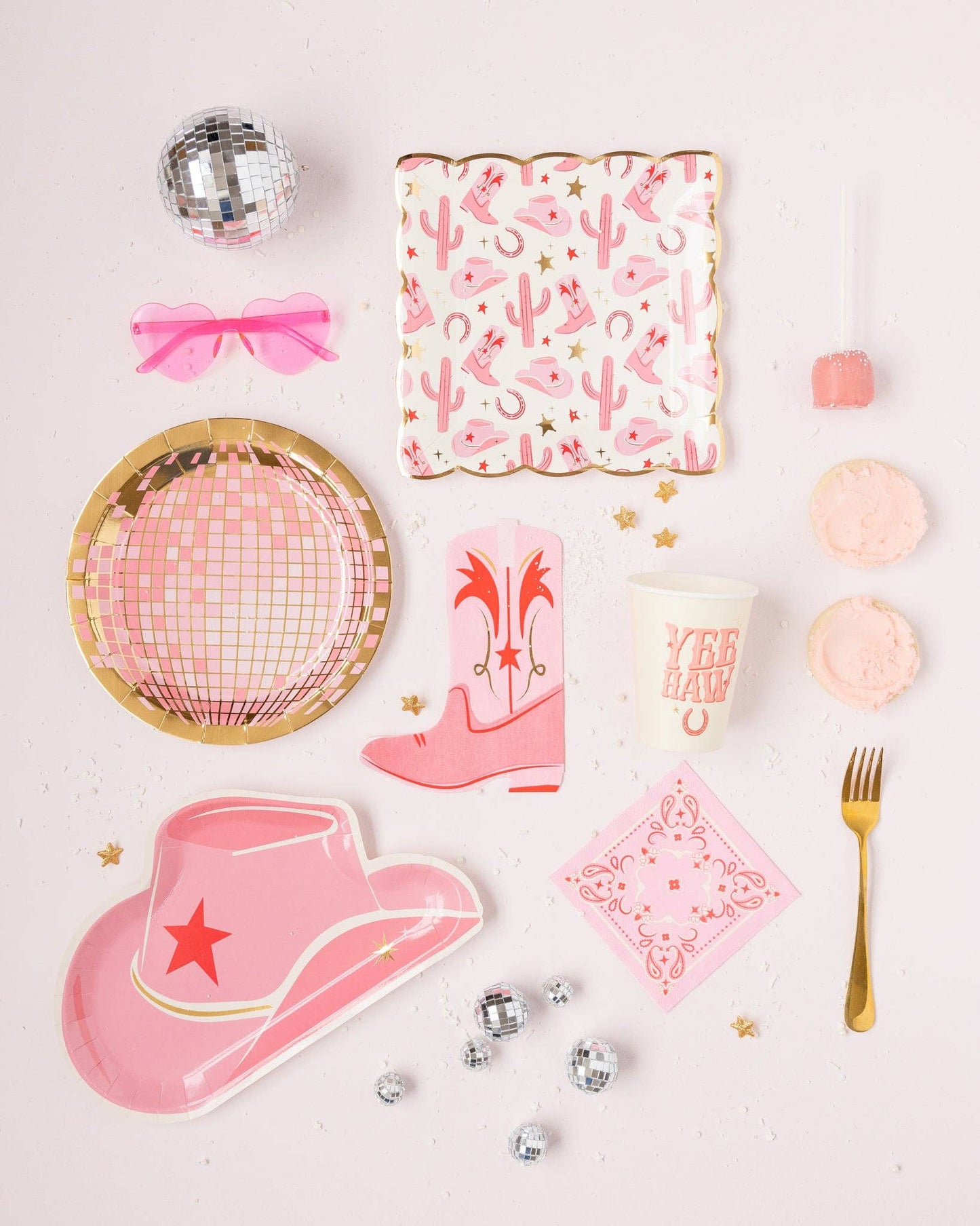 Pink western party supplies including plates, napkins and utensils on a light background