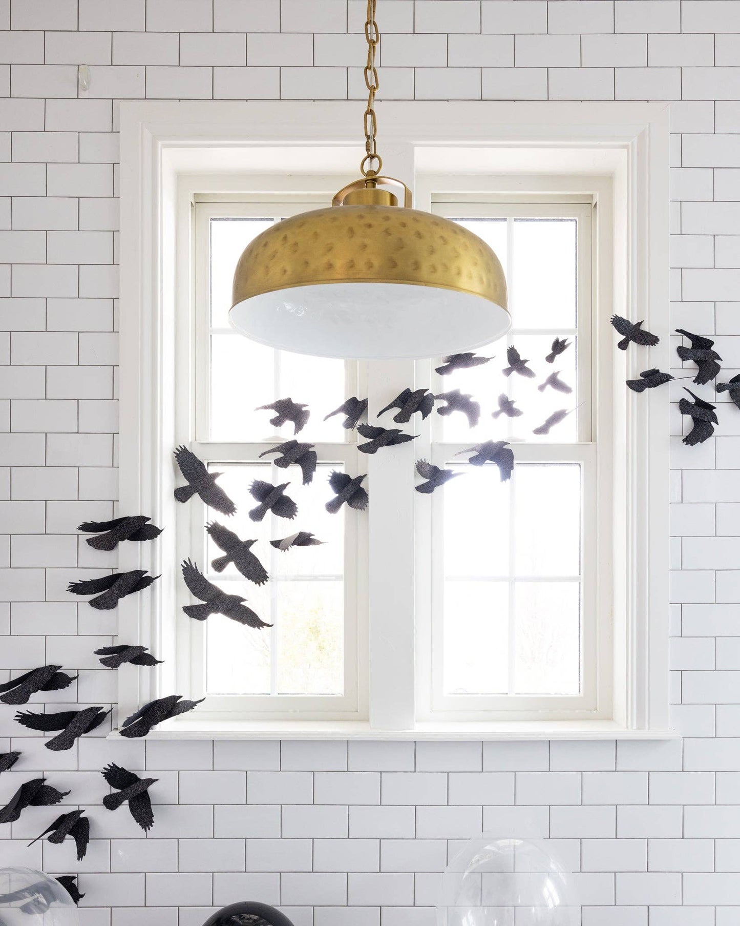 Close up of a bathroom window decorated with black glittered ravens as Halloween decor.