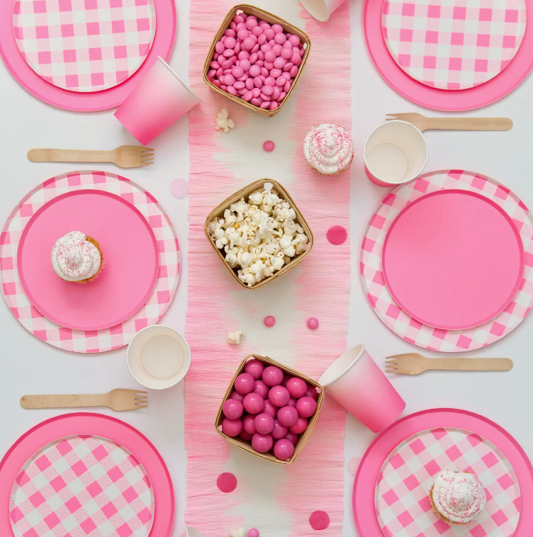 Laydown a pink tablescape featuring plates, cups and napkins