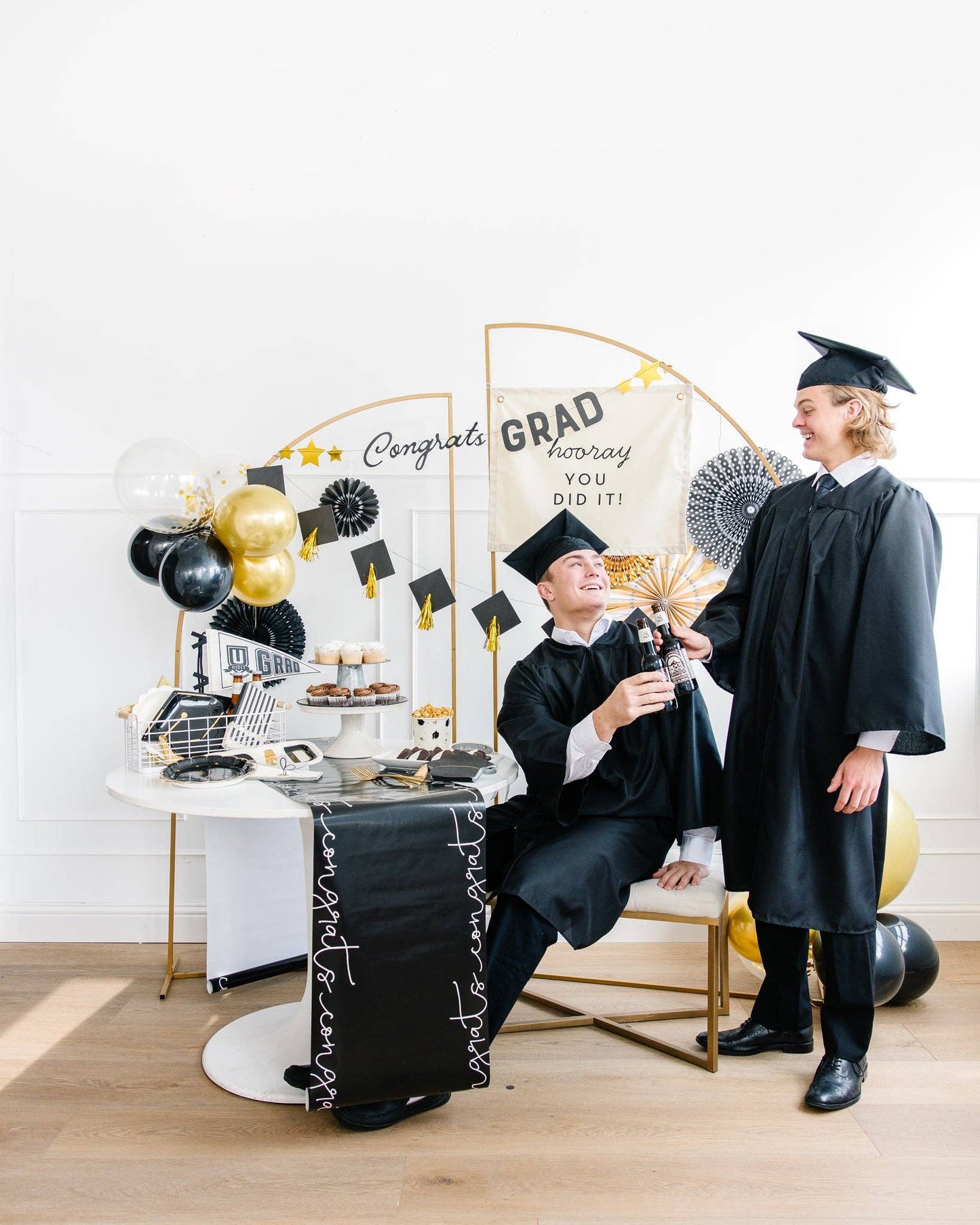 Graduation-themed party featuring two grads cheers-ing.