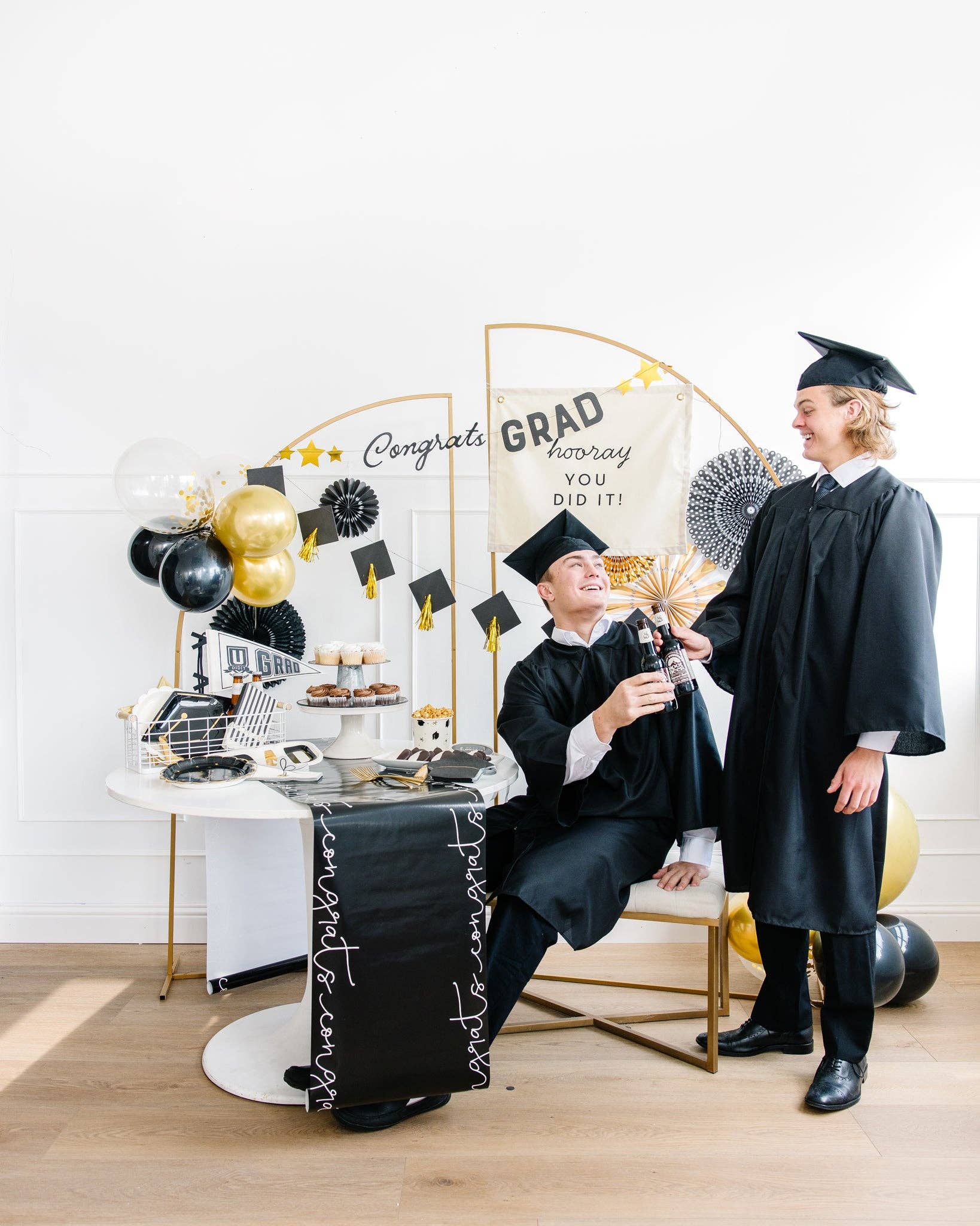 Graduation-themed party featuring two grads cheers-ing.