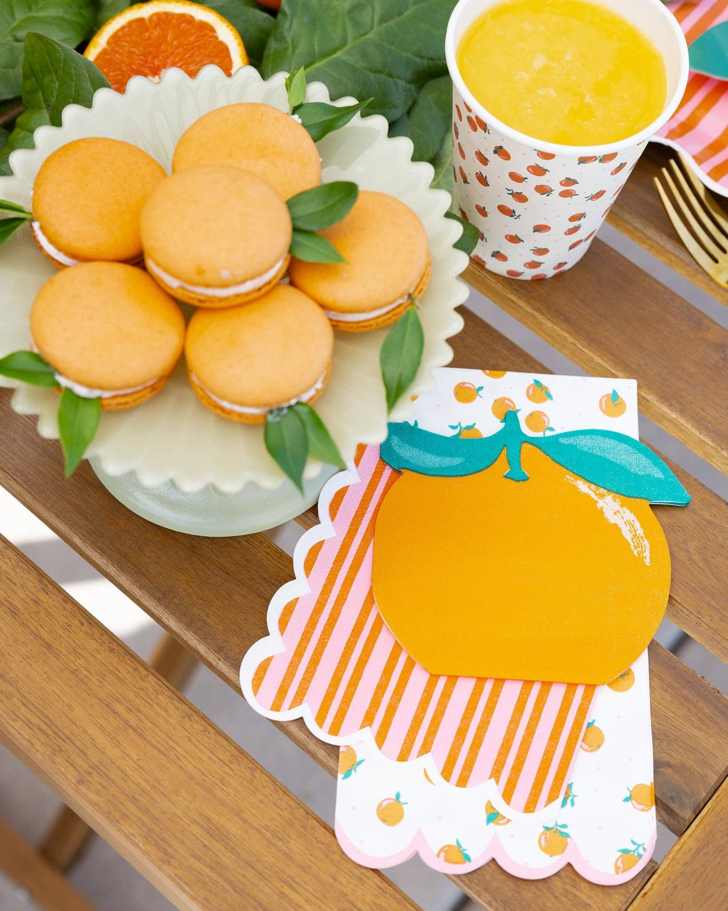 Citrus themed party with colorful napkins plates and cups on a wooden table.