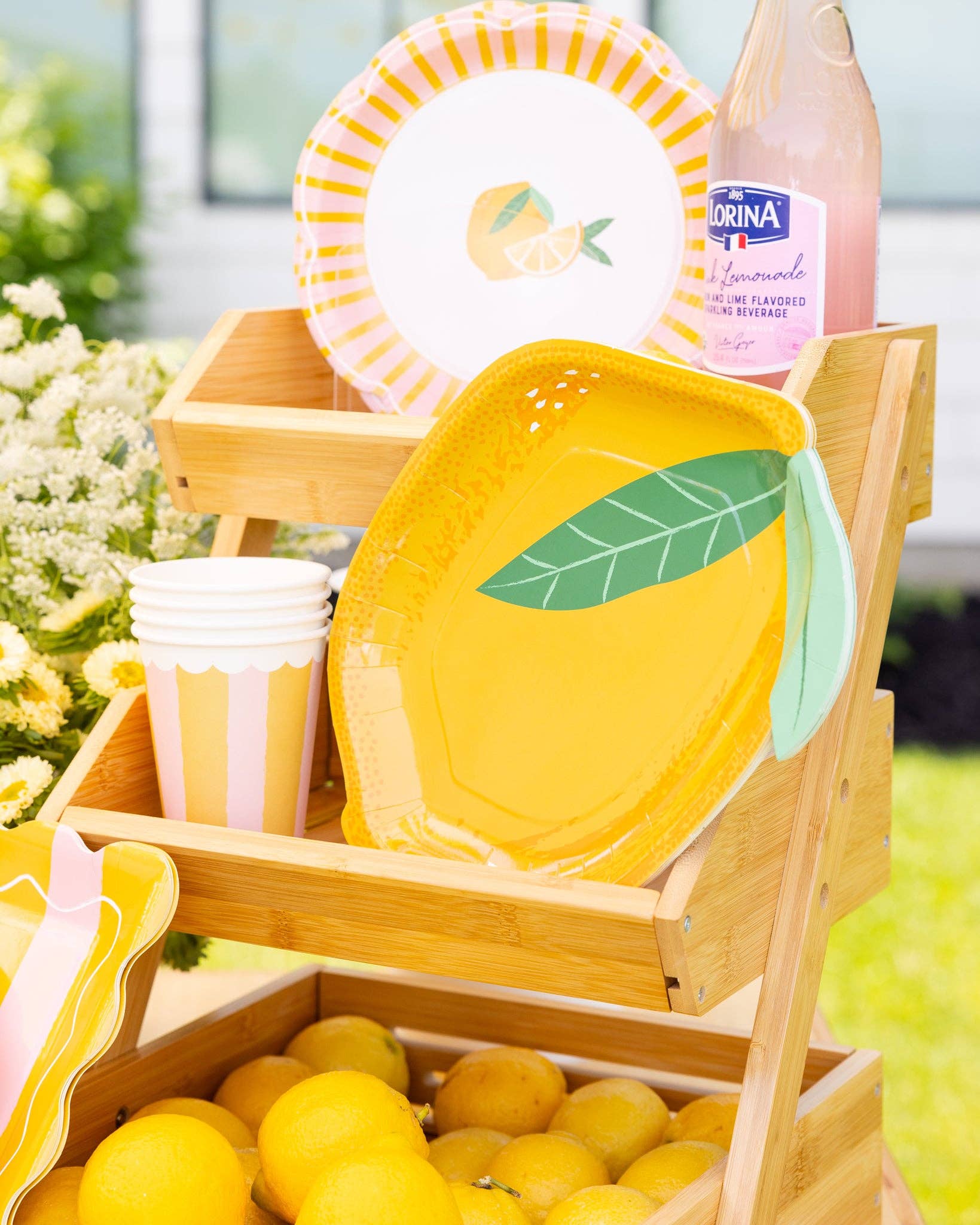 Yellow lemon plates on a wooden crate with cups and lemonade surrounding.