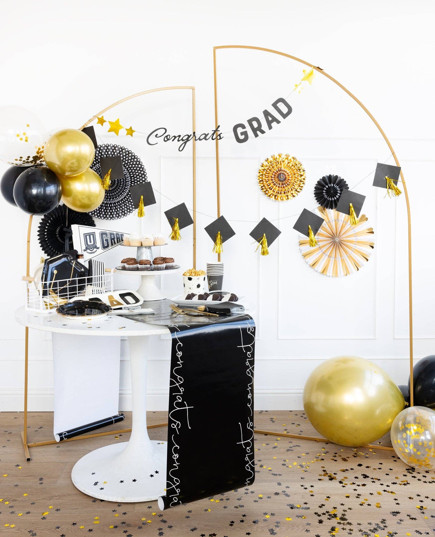 Graduation-themed party with balloons, arch, banners and table decorations.