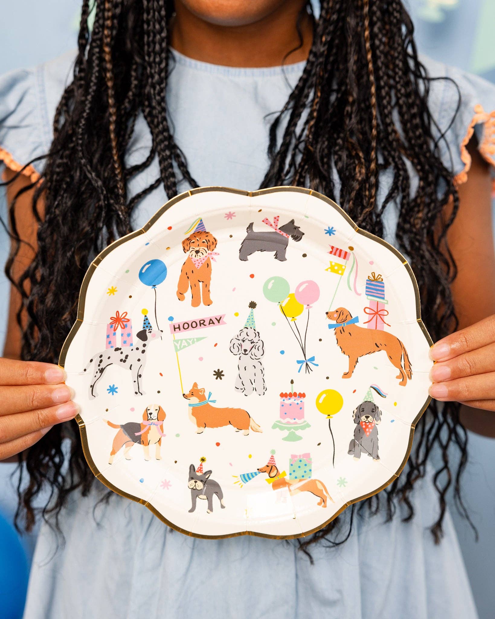 Person holding a decorative plate with illustrations of dogs at a party.