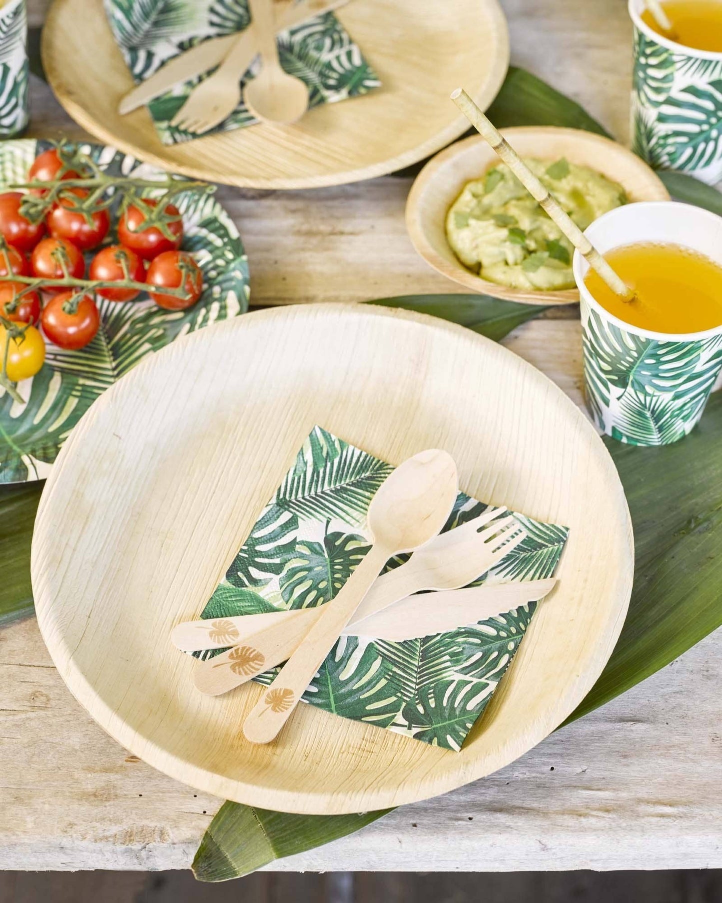 Bamboo bowls, wooden cutlery and leaf-printed cups on a table setting.
