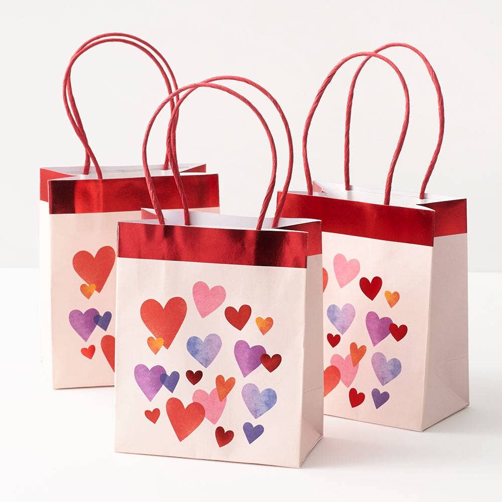 Three gift bags with colorful heart patterns on a white background