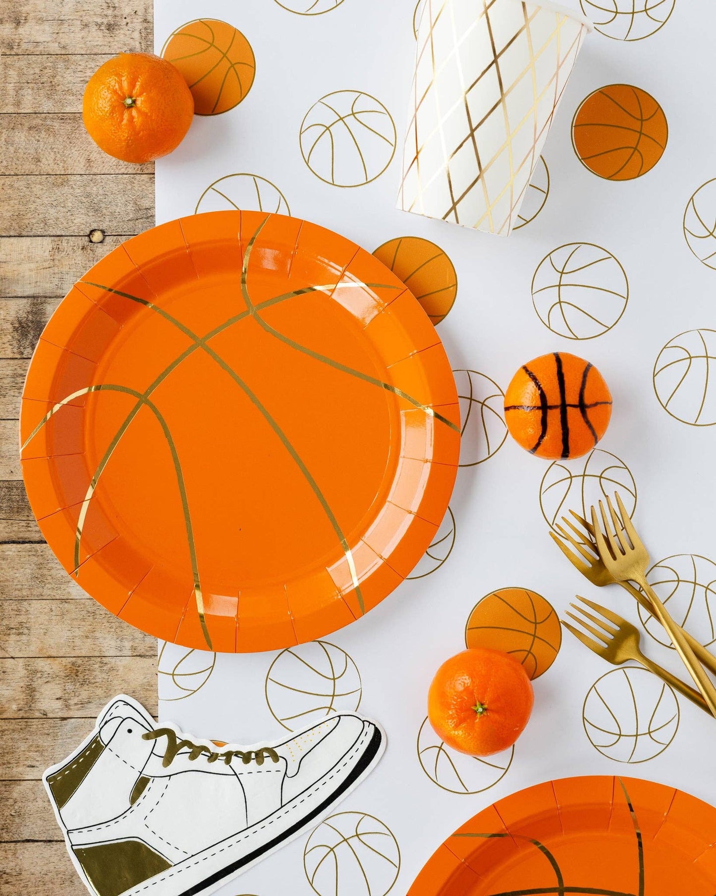 Basketball-themed party setup including plates, napkins on a table runner on a wooden surface.