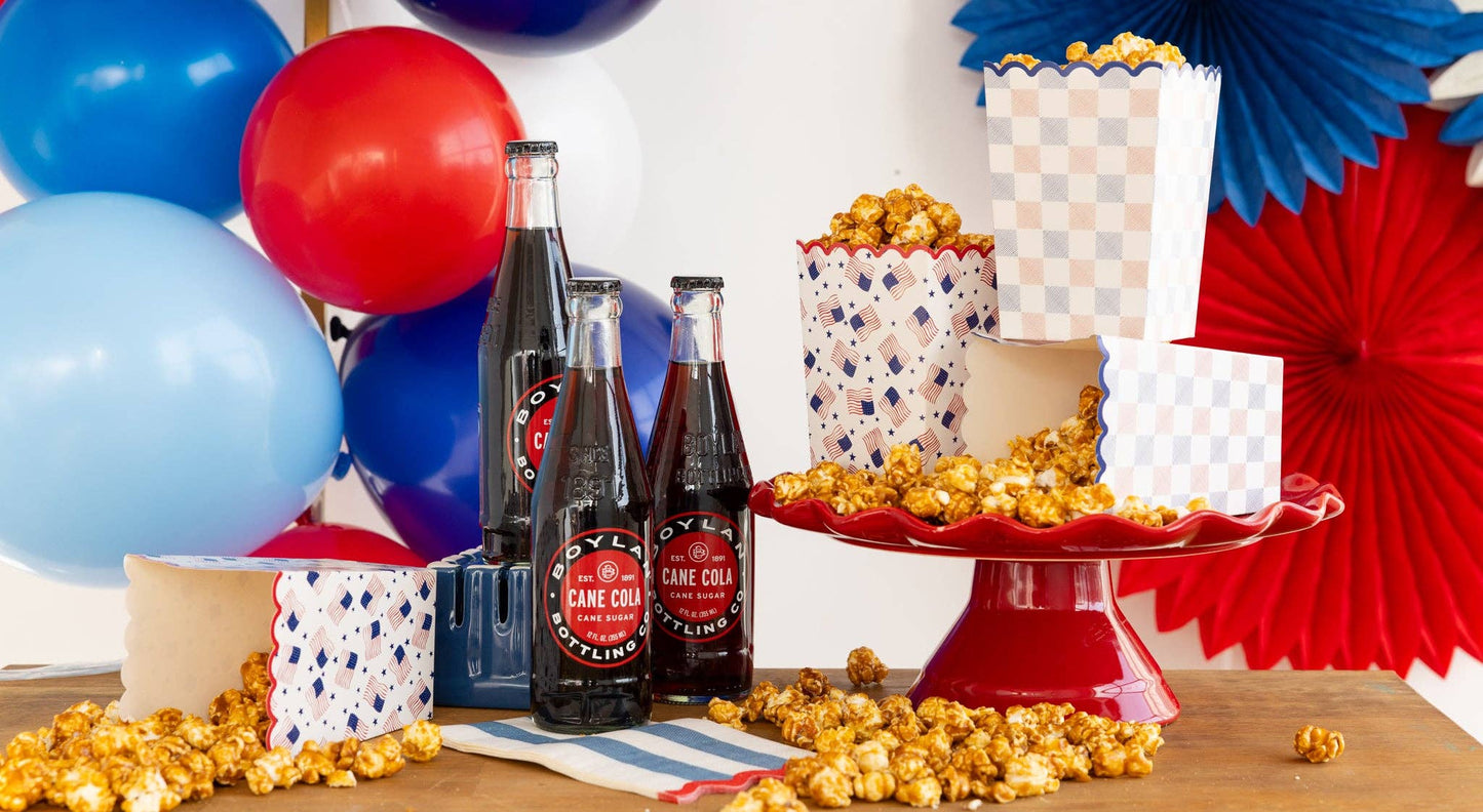 Party table with soda bottles, popcorn, and red, white and blue decorations.
