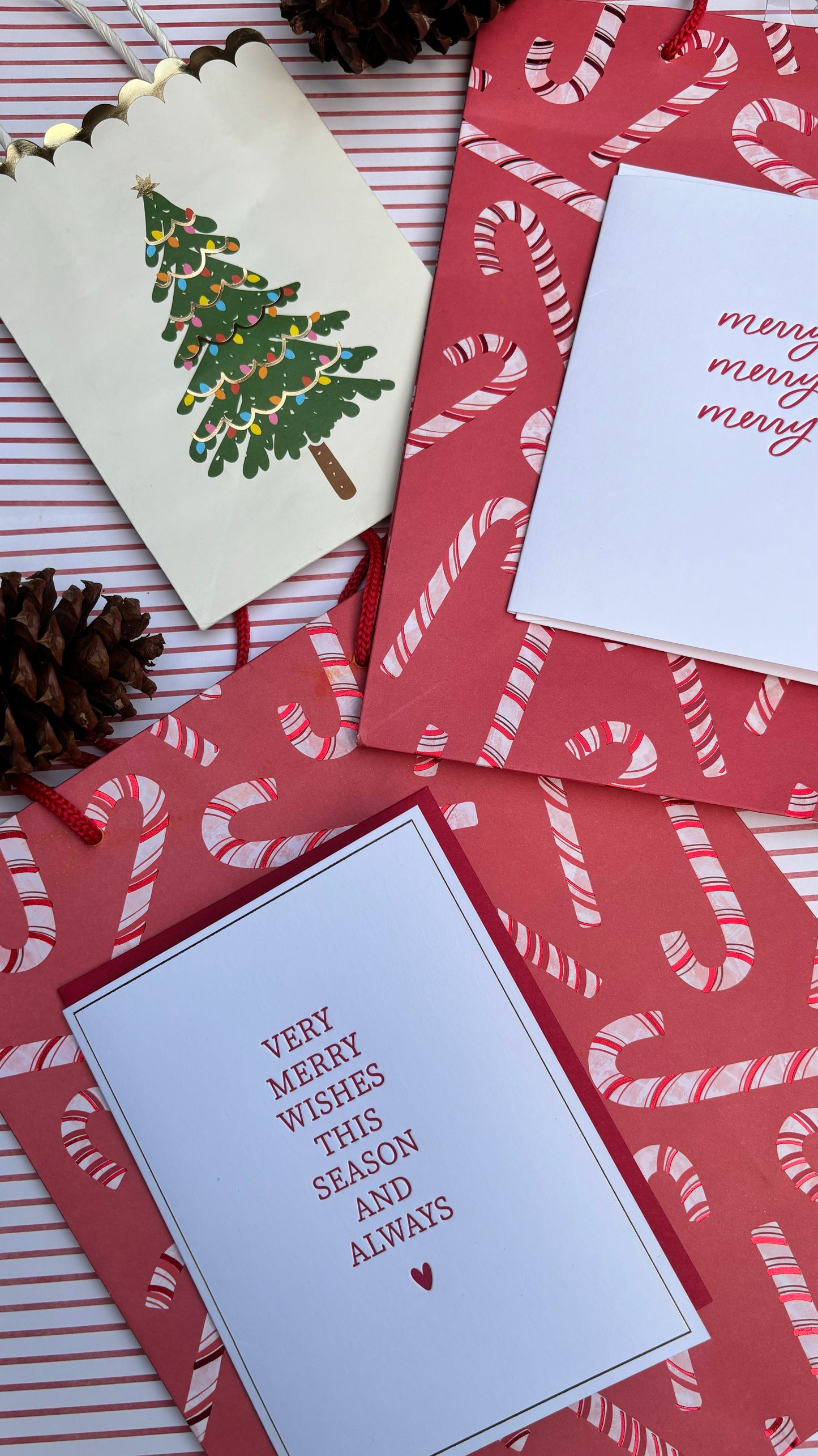 Image of a christmas card on white and red striped background with christmas bags also featured 