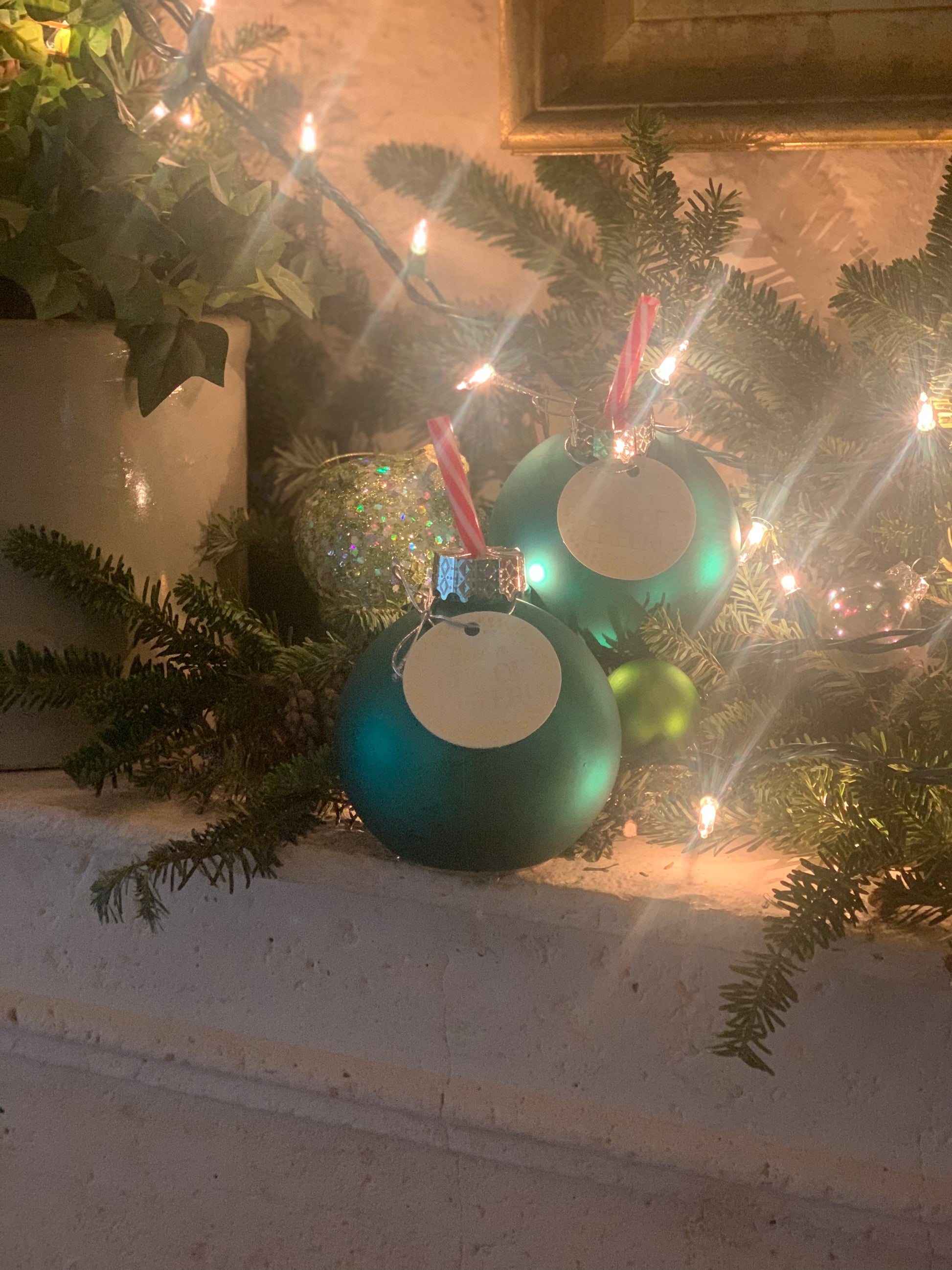 Image of a green ornament sipper with a peppermint printed straw on a decorative mantlepiece