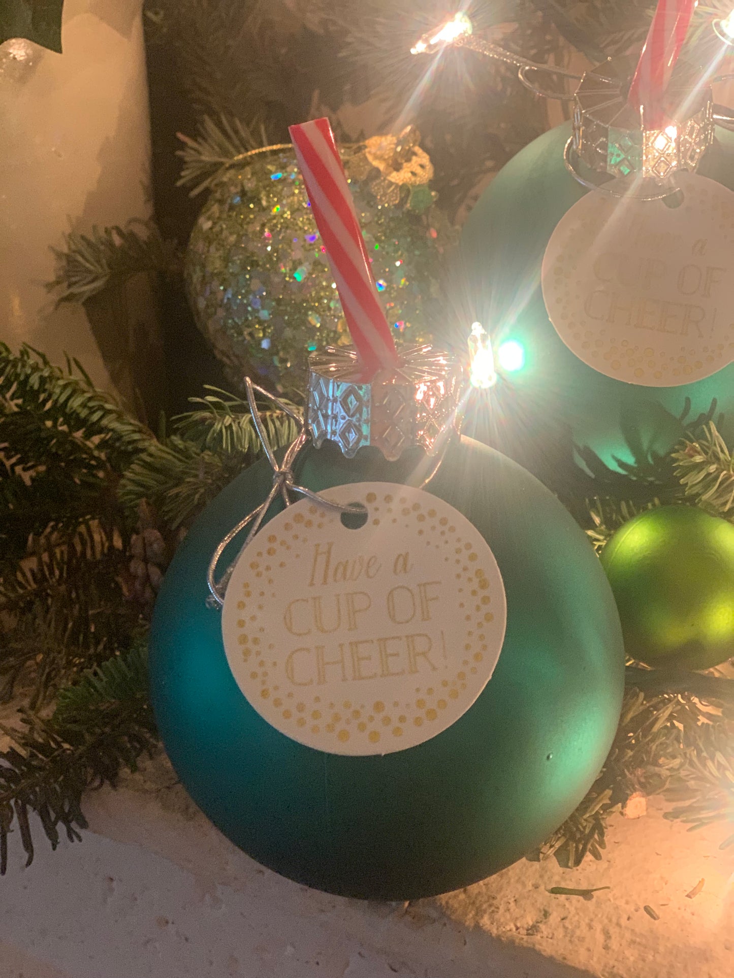 Image of a green ornament sipper with a peppermint printed straw on a decorative mantlepiece