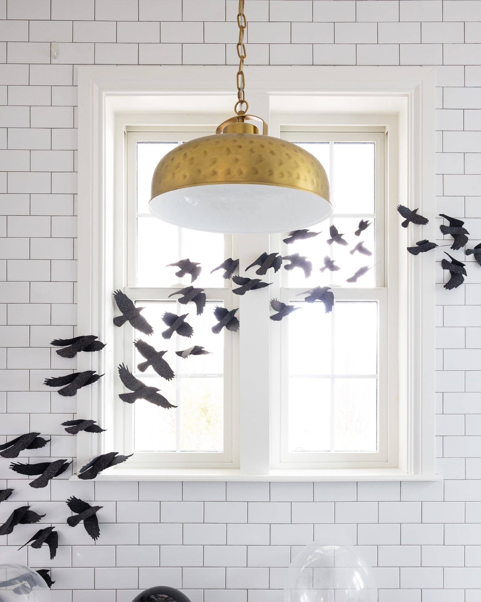 Close up of a bathroom window decorated with black glittered ravens as Halloween decor.