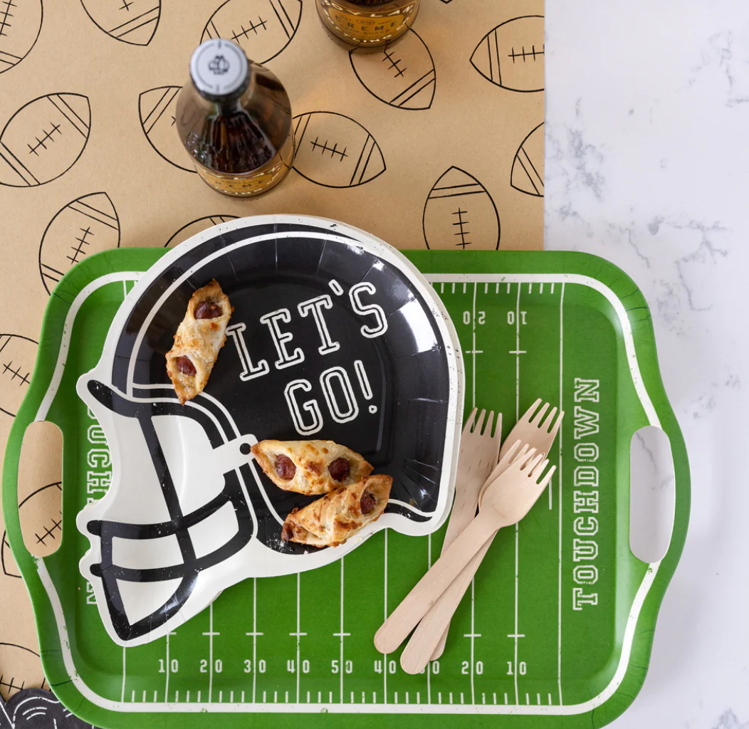 Bird's eye view image of a football party table featuring a helmet shaped plate and a football food tray