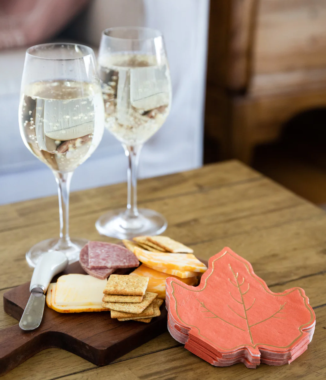 Image of an orange maple leaf napkin next to a meat and cheese board.