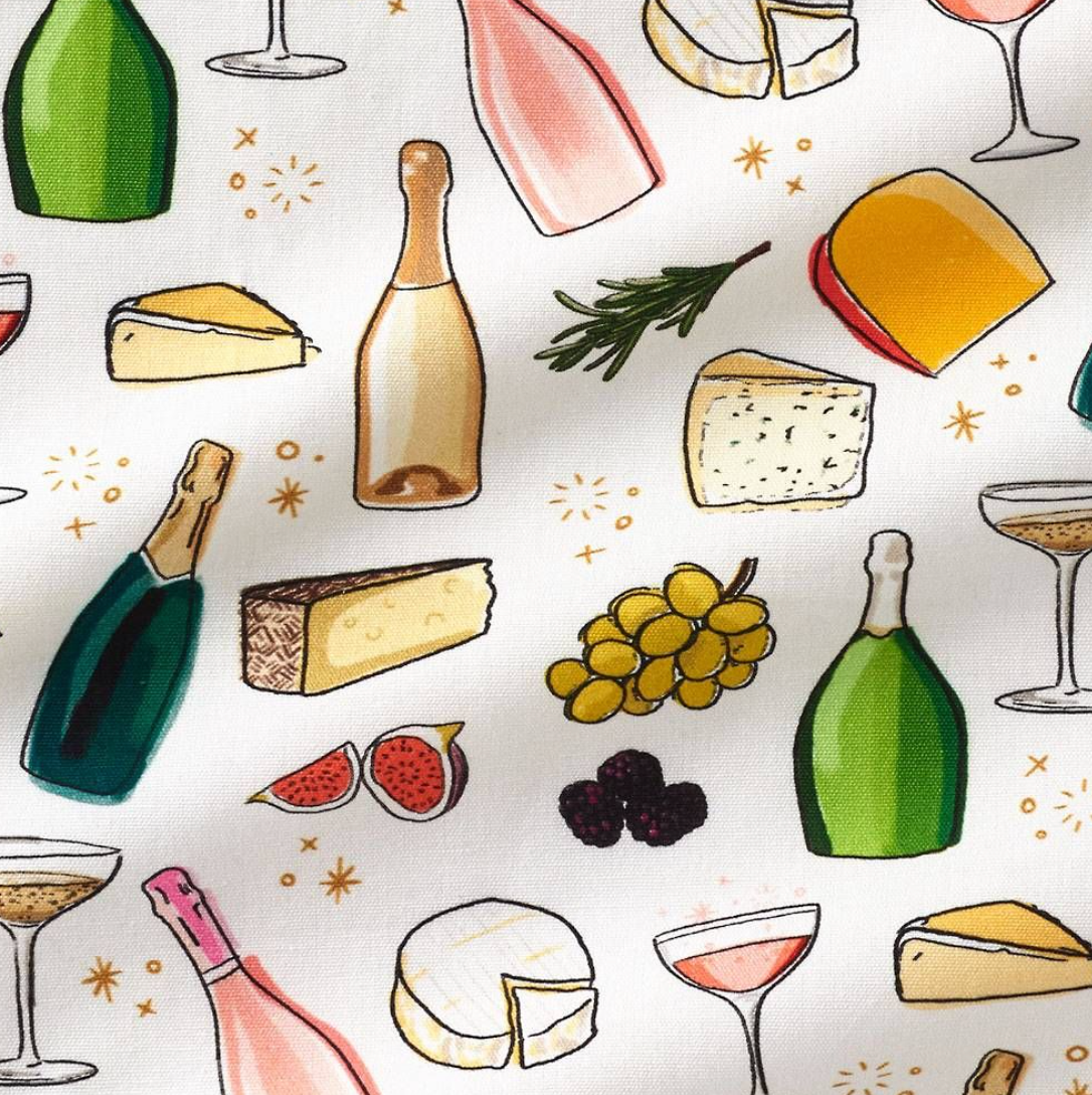 A close up of a tea towel featuring printed images of wine, champagne, cheese and fruit.