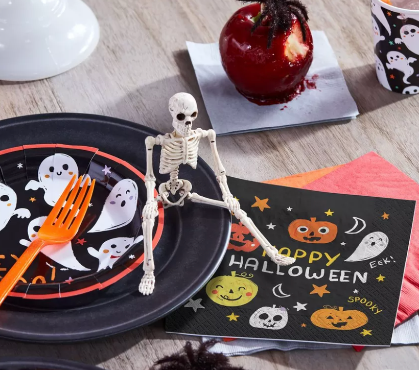 Image of a miniature plastic skeleton sitting on top of a Halloween plate