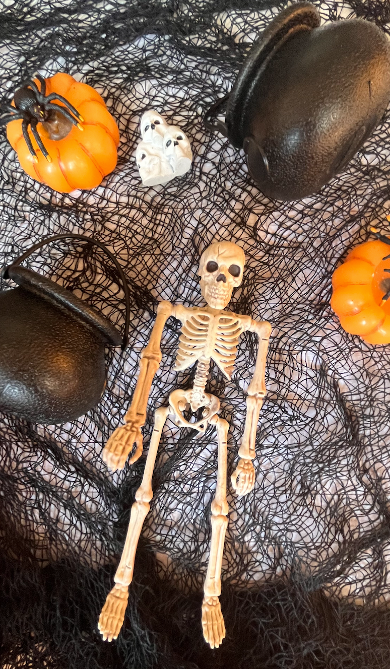 Image of a miniature plastic skeleton on top of spooky black gauze