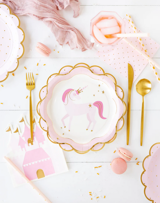 Pink princess-themed table setting with plates, cutlery and macarons on a table.