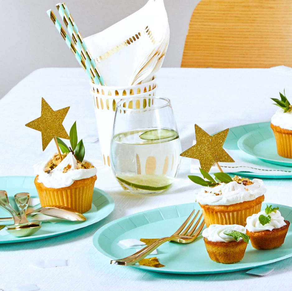 Table setting with cupcakes, glasses, and decorative stars on a white tablecloth.