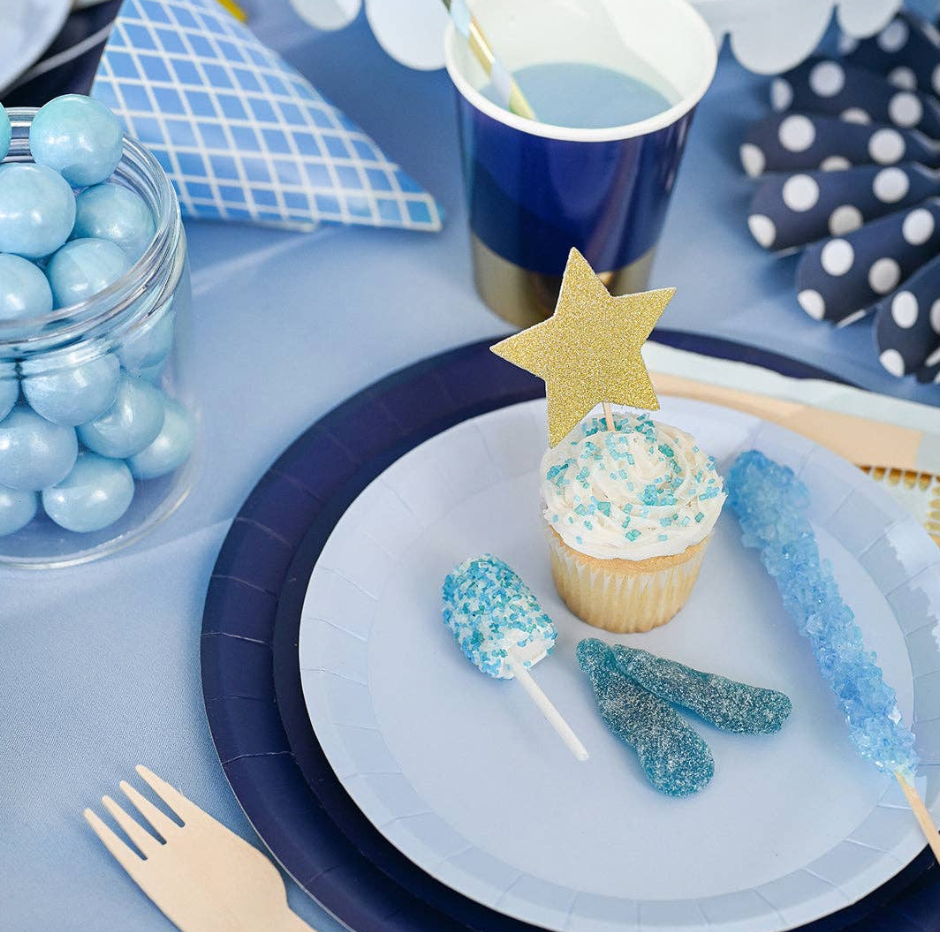 Party table setting with cupcake, candy, and decorations on a blue and white theme.