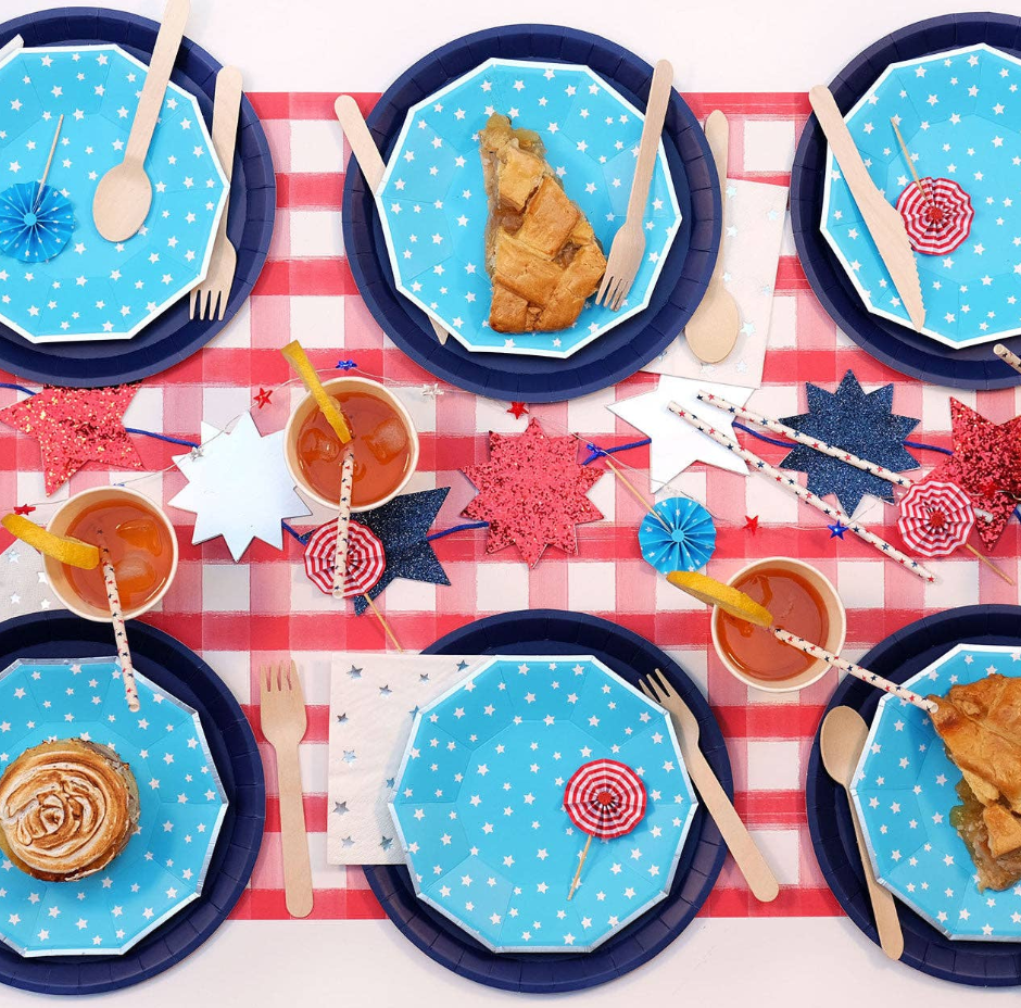 Table setting with blue plates, red and white checkered tablecloth, and festive decorations.