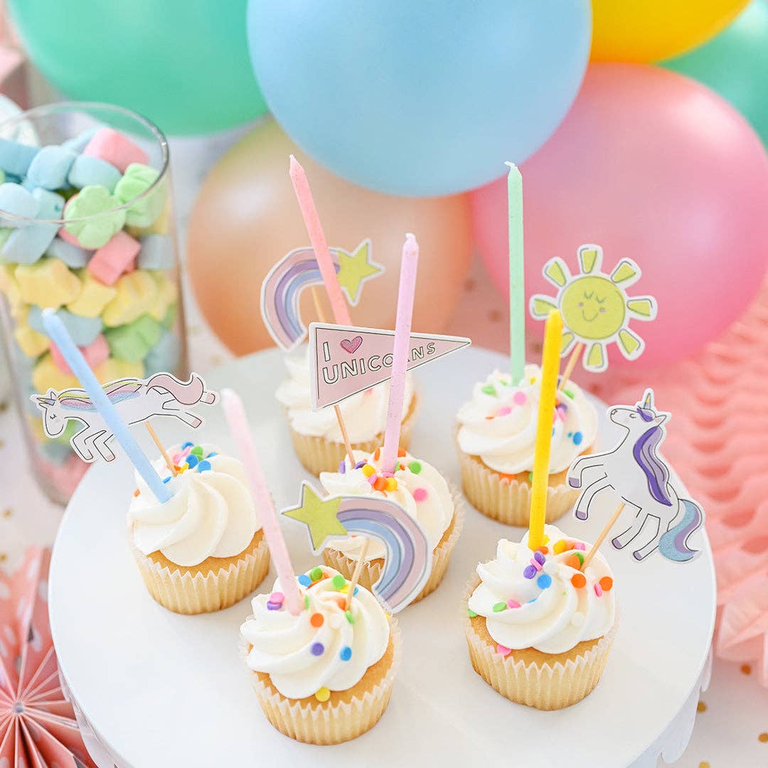 Cupcakes with decorative dessert  toppers on a table with balloons in the background.