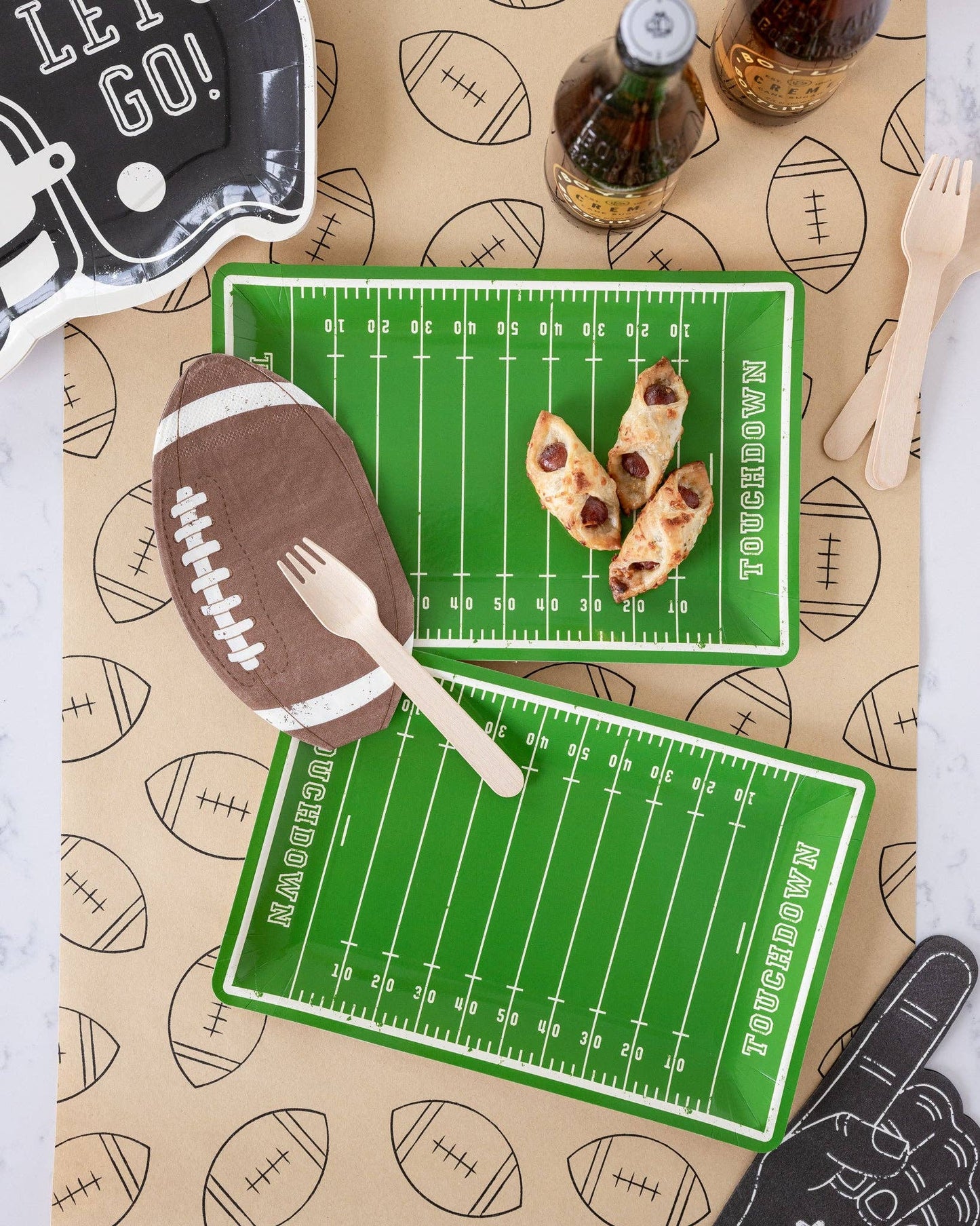 Football field plates with food and cutlery on a patterned table runner