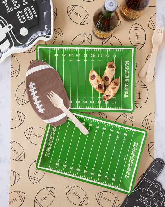 Football field plates with food and cutlery on a patterned table runner
