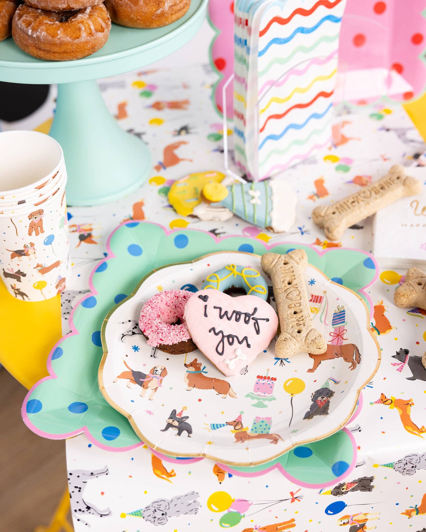 Colorful table setting with cookies, donuts and a decorative plate featuring dog illustrations.