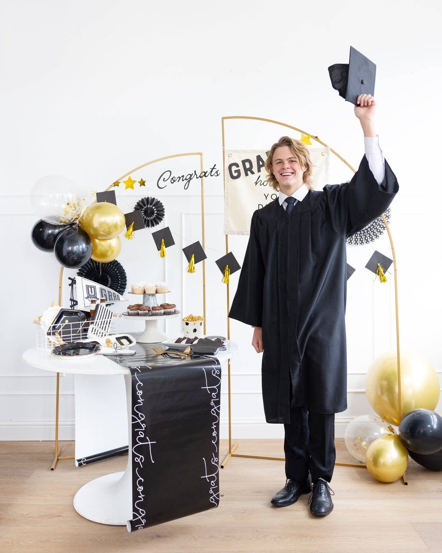 Graduate in cap and gown, surrounded by graduation-themed decorations.