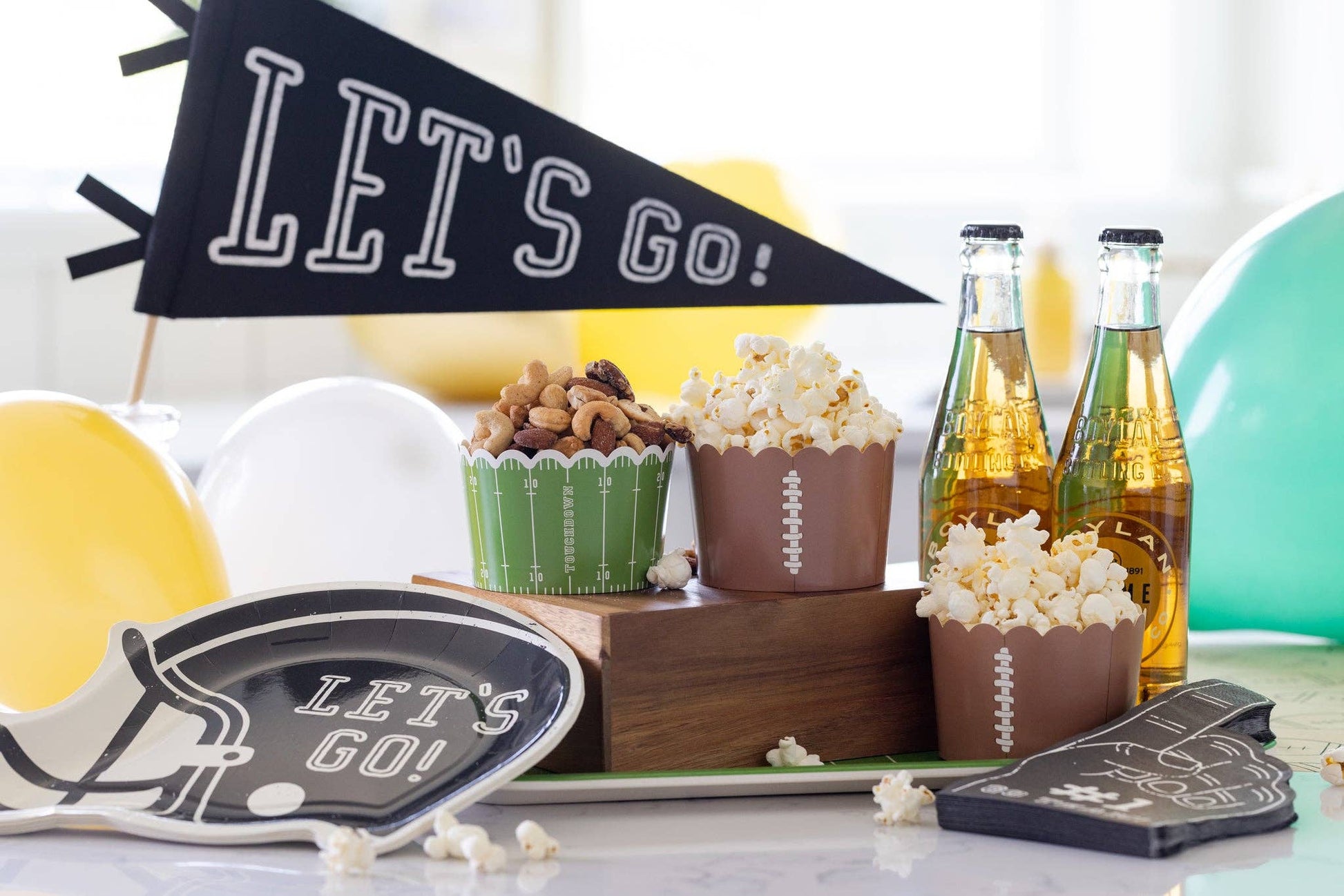 Gameday setup with snacks, drinks, and 'Let's Go!' decor on a table.