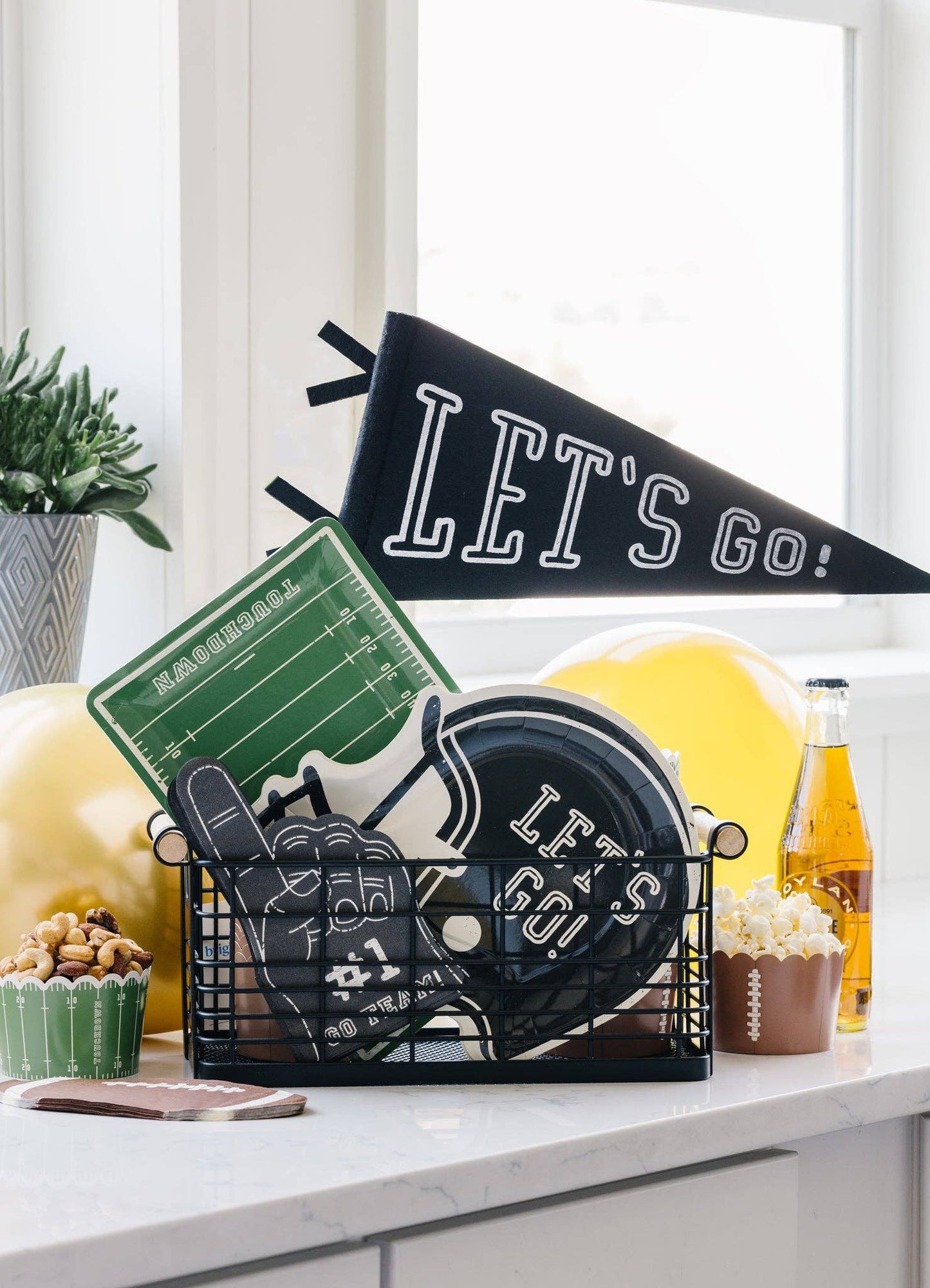Basket of football party supplies including a pennant, plate and napkins