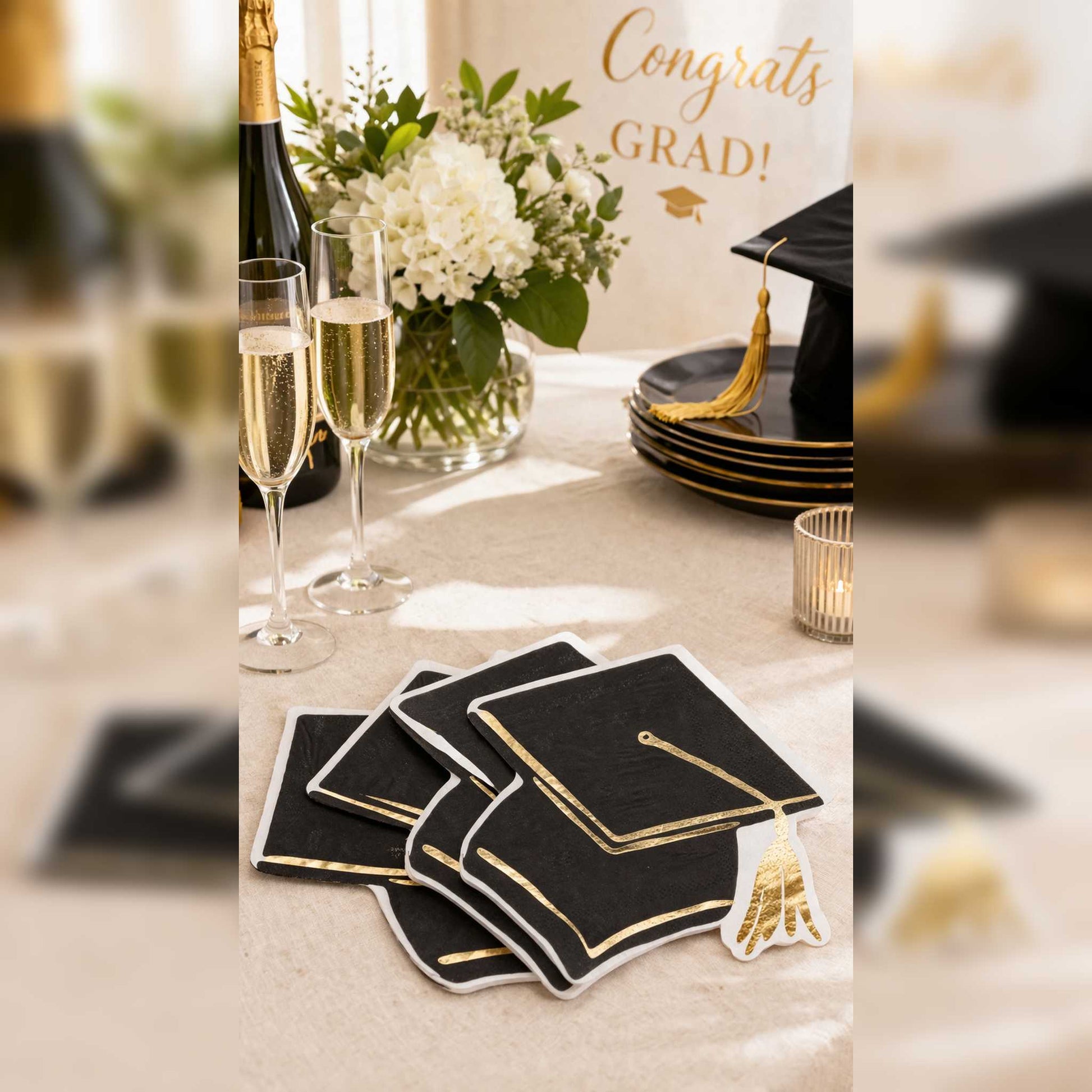 Graduation-themed table setting with champagne glasses, flowers and napkins.
