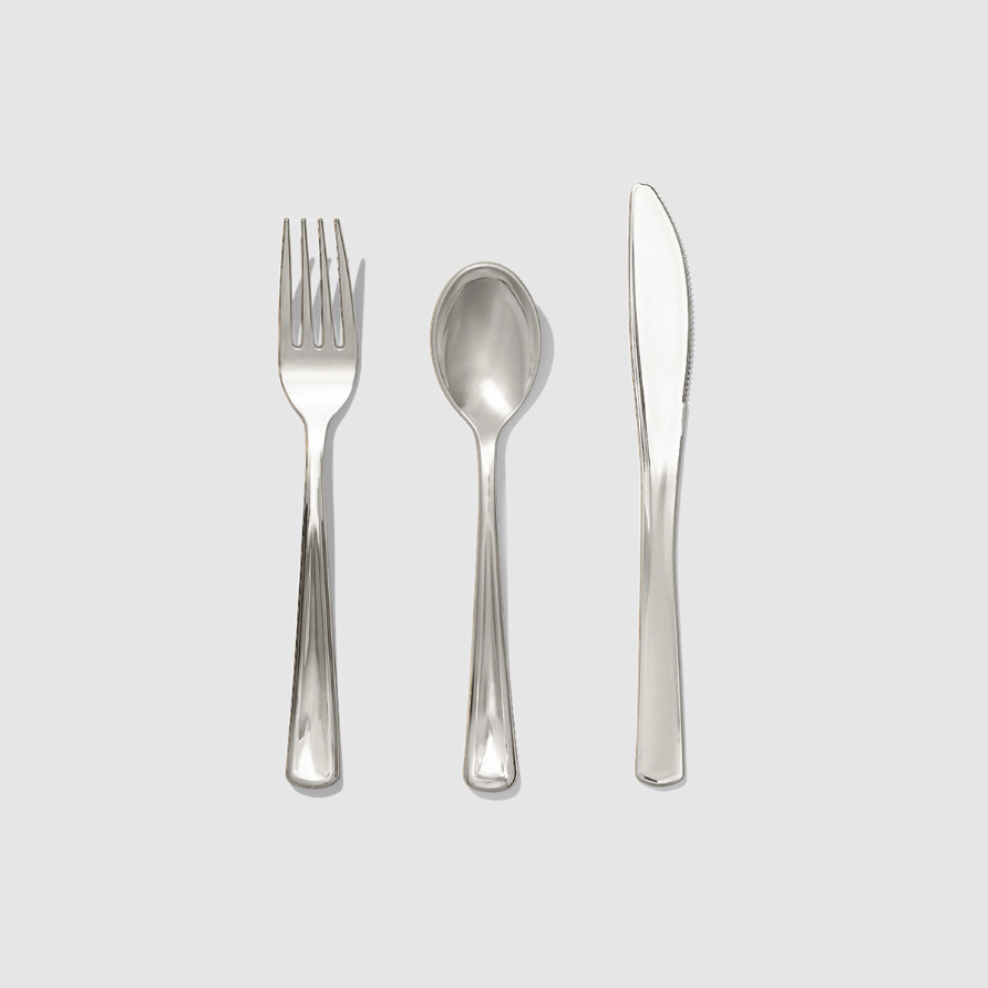 Set of silver fork, spoon, and knife on a light gray background