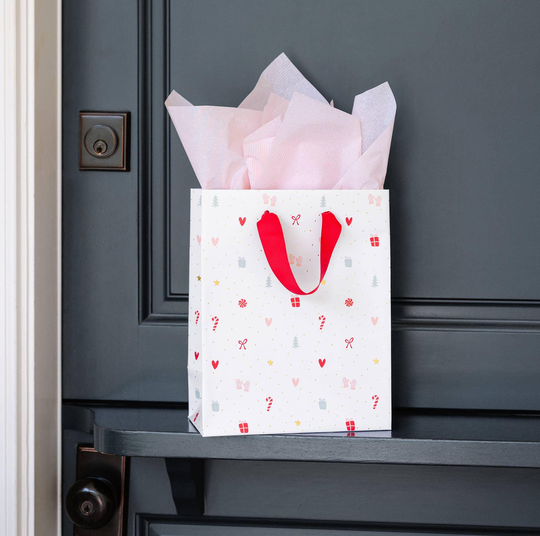 gift bag featuring christmas designs and a red ribbon handle