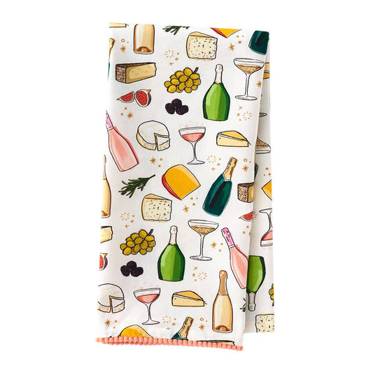 Tea towel featuring pom pom detailing and printed with images of wine, champagne, cheese and fruit.